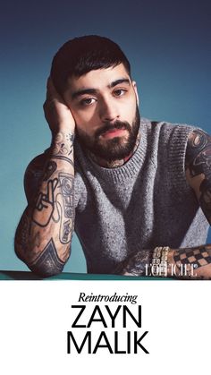 a man with tattoos on his arms and shoulder sitting in front of a blue background