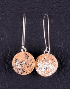 pair of earrings with silver and gold glitters on black background, close up photo