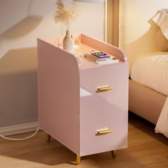 a pink night stand next to a bed