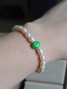 This pearl bracelet was carefully crafted by me on quality stretchy cord.  It's made with genuine cultured freshwater white rice pearls.  It has a single larger green pearl for a fun pop of color.  The bracelet measures 7 inches.  Perfect to be given as a gift or kept for yourself. It will coordinate with just about any outfit.  Please let me know if you have any questions.  If you need certain colors or lengths please reach out.  I'm happy to make a bracelet customized to your needs. Pearl Jewelry Gift, Rice Pearls, Freshwater Pearl Jewelry, Green Pearls, White Rice, I'm Happy, Stretch Bracelet, Pearl Bracelet, Stretch Bracelets