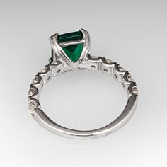 an emerald and diamond ring with white gold accents on the band, set in 18k white gold