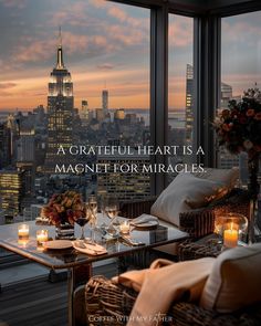 a table with candles and flowers on it in front of a window overlooking the city