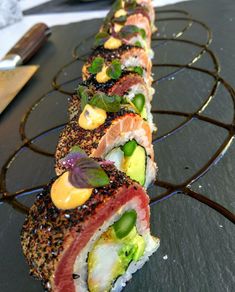 several sushi rolls are lined up on a metal rack with garnishes