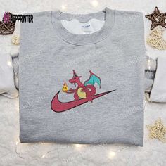 Introducing our Charizard x Nike Swoosh Anime Embroidered Sweatshirt, a fusion of style and nostalgia! This unique sweatshirt showcases a striking embroidered Charizard and Nike Swoosh design, creating a bold statement piece. Made with premium materials, it offers comfort and durability, perfect for everyday wear. The Pokemon Embroidered Shirt is a must-have for Pokemon enthusiasts. Featuring intricate embroidery of your favorite Pokemon characters, this shirt allows you to showcase your love fo Nike Anime, Nike Inspired, Sweatshirt Nike, Maroon Hoodie, Nike Design, Unique Sweatshirt, Embroidered Shirts, Anime Sweatshirt, Personal Narrative