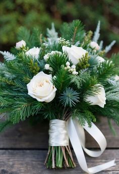 a bouquet of white flowers and greenery on a wooden table