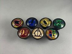 six harry potter glass knobs with the symbols on them, all in different colors