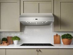 a stove top oven sitting inside of a kitchen next to wooden cutting boards and potted plants