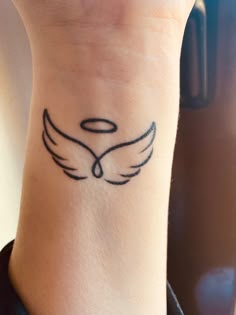 a woman's wrist with a small tattoo design on her left arm and an angel wing in the middle