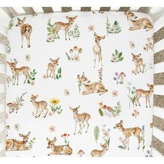 a baby crib with deers and flowers on it's blanket in white