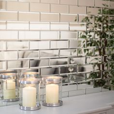 three candles sitting on top of a counter next to a mirror