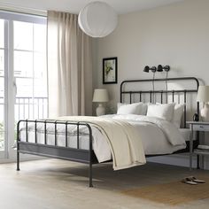 a bedroom with a metal bed frame and white linens on the pillows, along with an open door that leads to a balcony