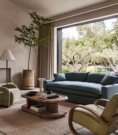 a living room filled with furniture and a large window overlooking the trees in the distance