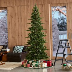 a small christmas tree in the middle of a living room with presents on the floor