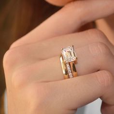 a close up of a person wearing a ring with an emerald stone on the side