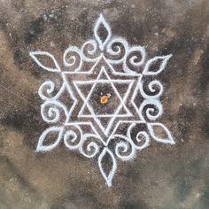 an intricate design is drawn on the ground with white chalk in front of it,