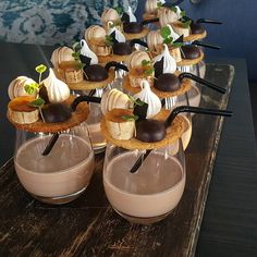 desserts are arranged in small glass dishes on a wooden table with black and white decorations