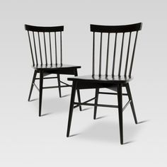 two black chairs sitting next to each other on a white surface with one chair facing the other