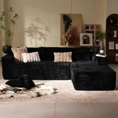 a living room with black couches and rugs on the floor in front of it