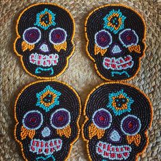 three embroidered sugar skulls sitting on top of a woven tablecloth covered placemats