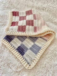 two crocheted dishcloths laying on top of a white blanket covered in fur