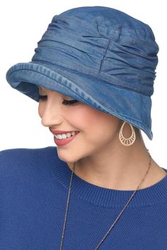 a woman wearing a blue hat with large hoop earrings on her ear and smiling at the camera