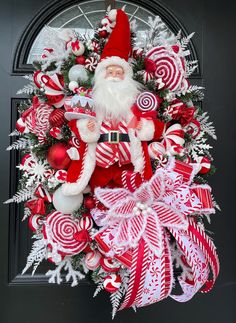 a christmas wreath with santa claus and candy canes on it, hanging from the front door