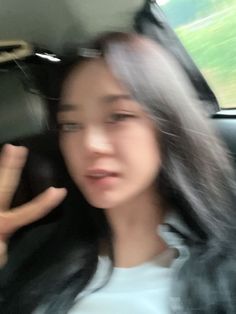 a woman sitting in the back seat of a car making a peace sign with her hand