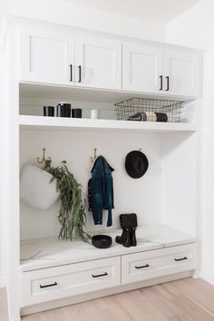 a white coat rack with hats, boots and other items on it in a room