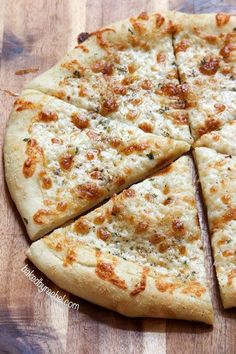 a pizza that is cut into four pieces on a cutting board with cheese and seasoning