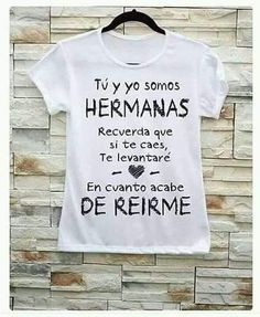 a white t - shirt hanging on a brick wall with words written in spanish and english