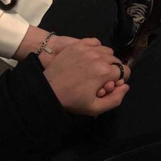 two people holding hands with one wearing a cross bracelet and the other in a white shirt