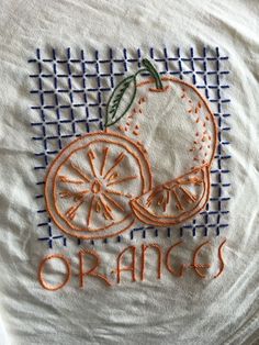 an orange embroidered onto a white t - shirt