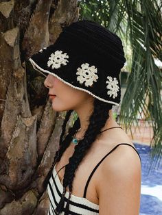 a woman wearing a black and white hat next to a tree