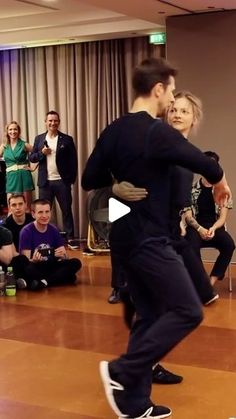 two people are dancing in front of an audience and one person is holding his arm around the other