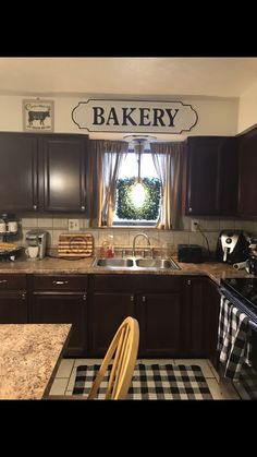 a kitchen with brown cabinets and a window that says bakery on the wall above the sink