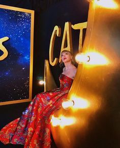 a woman in a red dress sitting on the side of a sign that says cats