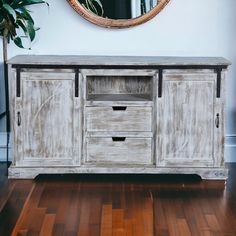 an old white sideboard with two drawers and a mirror on the wall behind it