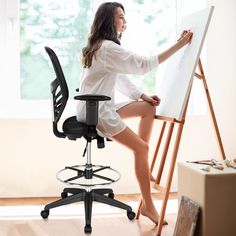 a woman sitting in an office chair drawing on a white board