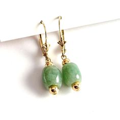 Vintage 14K Yellow Gold Wire Jadeite Dangle Earrings. The beautiful light green jade beads are approx 8mm around and 9mm long. These earrings measure about 1 1/4" long. They are marked 14K on the latch back and weigh about 2.7 grams. They are in good condition with light to no wear. Add these pretty genuine jade earrings to your collection today!  Visit our FAQ section: https://www.etsy.com/shop/KayZees?ref=hdr_shop_menu#more-section If you have any questions please don't hesitate to ask! Green Polished Bead Earrings, Green Earrings With Polished Round Beads, Elegant Jade Gemstone Beads Earrings, Elegant Jade Earrings With Gemstone Beads, Elegant Green Gemstone Beaded Earrings, Green Jade Gemstone Bead Earrings, Green Jade Earrings With Gemstone Beads, Golden Co, Jade Earrings