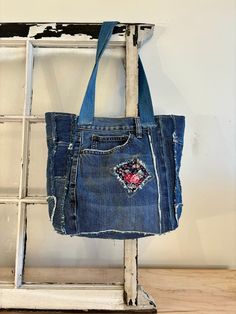 an old pair of jeans is hanging on a ladder with a handbag in it