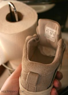 a person holding a pair of shoes in front of two rolls of toilet paper