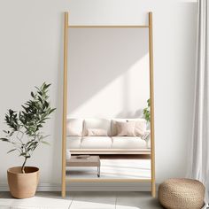 a living room with a white couch and potted plant in front of the mirror