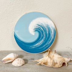 two seashells and a blue plate on a wooden table with a white wall in the background