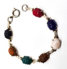 a bracelet with five different colored stones on it's clasp and two charms attached to the clasp