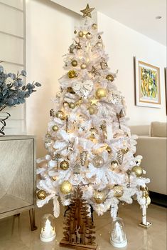 a white christmas tree with gold and silver ornaments