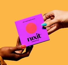 two hands holding a pink box with the word nixtt on it and an orange circle