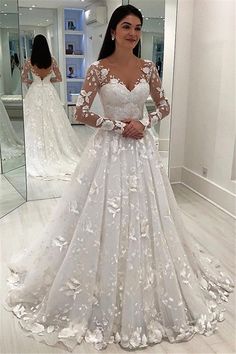 a woman standing in front of a mirror wearing a wedding dress with flowers on it