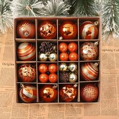 an open box filled with christmas ornaments on top of a newspaper next to a tree