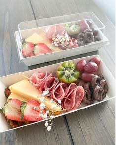 two trays filled with different types of food on top of a wooden table next to each other