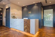 the front desk of a hotel lobby with wood flooring and blue walls, along with white marble counter tops